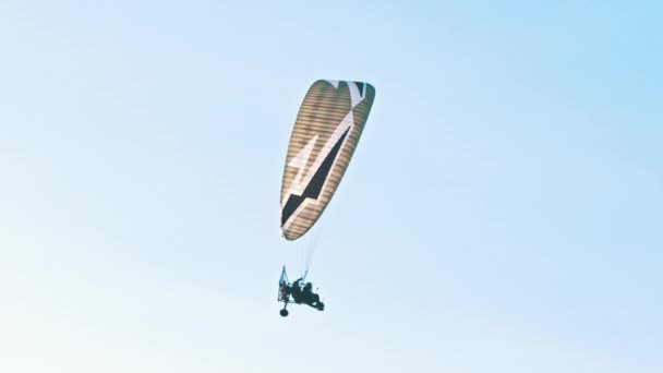 Tandem paramotorgliding, δύο αλεξίπτωτα πλαγιάς που πετούν πάνω από το φωτεινό γαλάζιο του ουρανού — Αρχείο Βίντεο