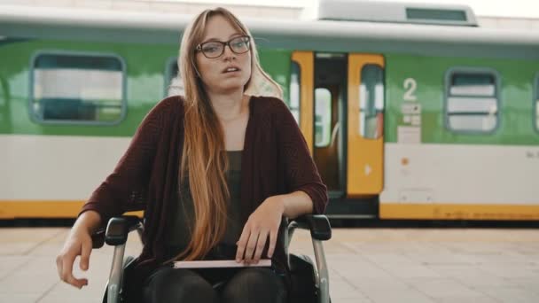 Varsavia, Polonia 09.04.2020 - giovane donna triste e scoraggiata sulla sedia a rotelle della stazione ferroviaria. Treno in partenza — Video Stock