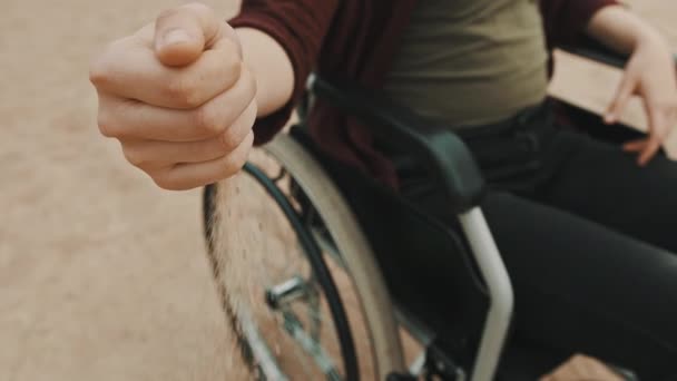 Zblízka, ruka osoby se zdravotním postižením na invalidním vozíku hraje s pískem na pláži — Stock video