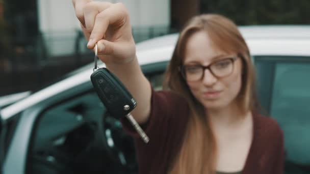 젊은 코카서스 출신의 행복 한 여자가 새 차 앞에서 열쇠를 들고 천천히 움직이는 모습 — 비디오