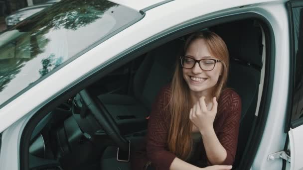 Yeni arabasının şoför koltuğunda oturan beyaz kadının mutlu yüz ifadesi. — Stok video