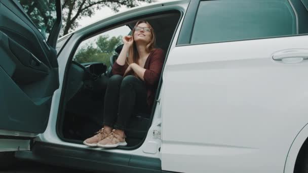 Expresión de la cara feliz de la joven mujer caucásica sentada en el asiento del conductor de su nuevo coche — Vídeos de Stock