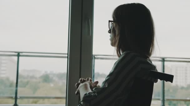 Depressieve jonge gehandicapte vrouw bij het raam met hoofdpijn — Stockvideo