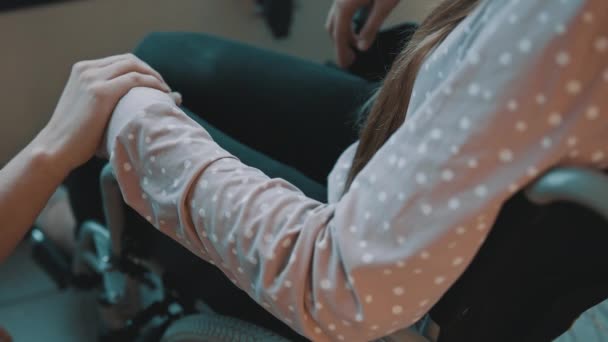 Tutup, tangan mengulurkan tangan ke tangan wanita muda tertekan di kursi roda — Stok Video
