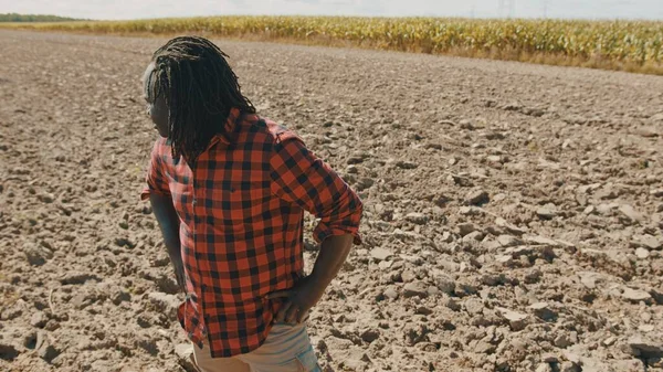 Joven agricultor africano parado en la tierra arada agrícola — Foto de Stock