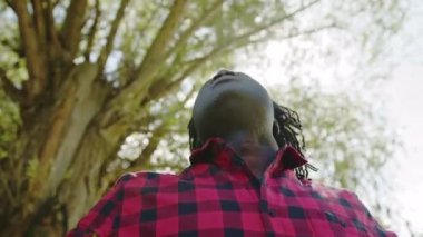 Afrikalı adam derin bir nefes alır ellerini kaldırır ve gökyüzüne bakar. Ağaçtan gelen güneş ışınları. Umut ve dua kavramı