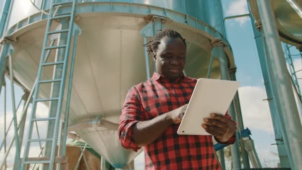 Agricultor africano usando laptop na frente do sistema de armazenamento de silo — Vídeo de Stock