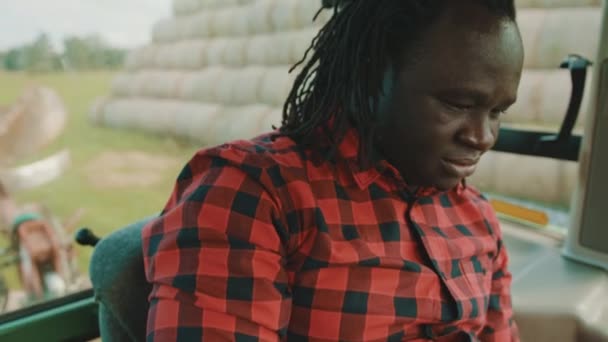 Jovem agricultor africano usando tablet enquanto sentado na cabine do trator — Vídeo de Stock