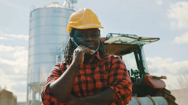 A boldog afrikai gazda portréja a traktor és siló rendszer előtt — Stock Fotó