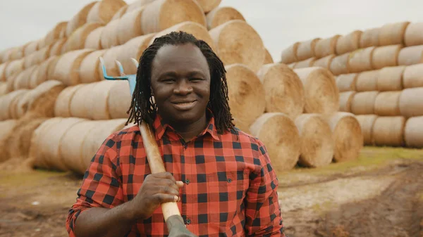 Portrét mladého afrického farmáře s vidlemi přes rameno — Stock fotografie