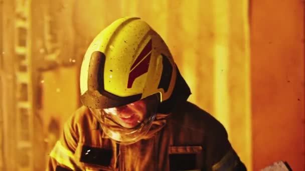 Porträtt av ung brandman ta bort bränt trä från brinnande hus — Stockvideo