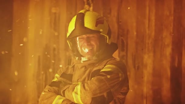 Retrato de jovem bombeiro na frente da casa em chamas sorrindo em uniforme completo — Vídeo de Stock