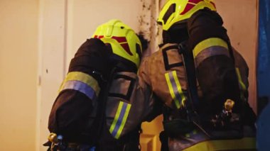 İtfaiyeciler yanan kapıları kırıyor.