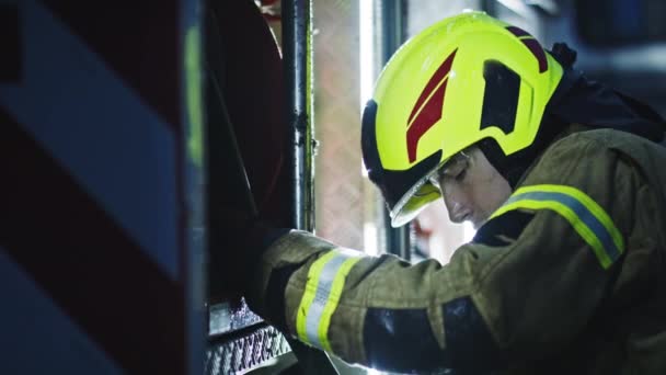 Jonge brandweerman controleert de slang op de brandweerauto — Stockvideo