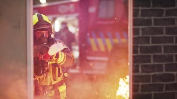 Il pompiere spegne il fuoco con il tubo. Trapano antincendio della casa in fiamme — Video Stock