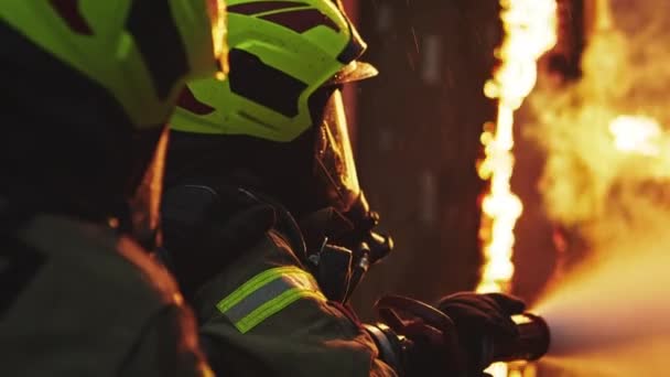 Los bomberos apagan el fuego con la manguera. Taladro de incendio de la casa en llamas — Vídeos de Stock