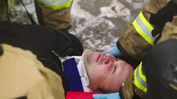 Brandmän lyfter en skadad man. Räddning efter bilolycka — Stockvideo