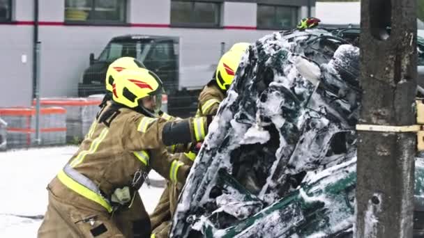 Пожарные разворачивают разбитую машину после тушения огня — стоковое видео