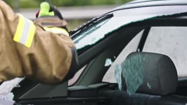 Firefighter beraking glass on car window extricate trapped victim from the car — Stock Video