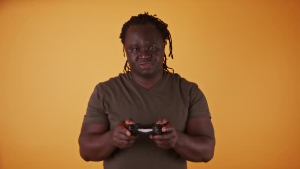 Hombre africano con controlador de juego aislado sobre fondo naranja — Vídeos de Stock
