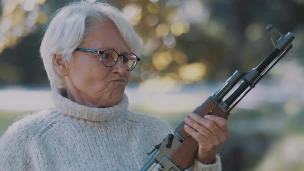 Eine ältere grauhaarige Frau mit einer Waffe in der Hand. Konzept Krieg oder Revolution — Stockvideo