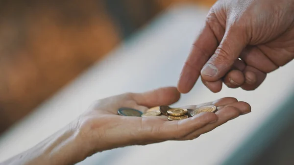 閉じ、男性の手高齢者のホームレスの女性にコインを与える。慈善と支援の概念 — ストック写真