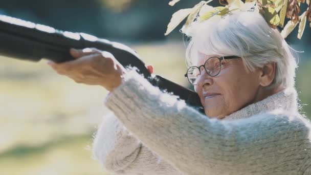 Anciana mujer de pelo gris sosteniendo un arma en sus manos. Guerra o concepto de revolución — Vídeos de Stock