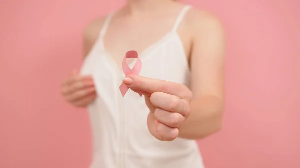 Październik, wstążka uświadamiająca raka w ręce młodej, nie do odróżnienia kobiety. — Zdjęcie stockowe