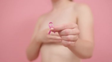 Yaklaş, parmaklarının arasında pembe ipek kurdele tutan kadın. Göğüs kanseri farkındalığı ayı pembe Ekim