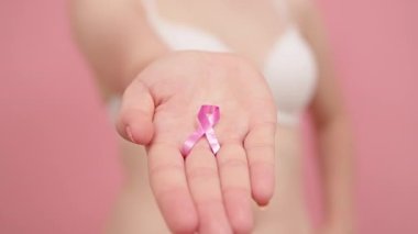 Yaklaş, parmaklarının arasında pembe ipek kurdele tutan kadın. Göğüs kanseri farkındalığı ayı pembe Ekim