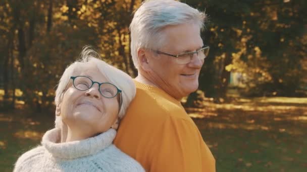 Amor y afecto a la vejez. Pareja jubilada disfrutando del día de otoño en el bosque — Vídeos de Stock