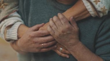 Kırışık elleri kapayın. Parkta kucaklaşan mutlu yaşlı çift. Kıdemli adam yaşlı bir kadınla flört ediyor. Yaşlılıkta aşk Sonbahar günü dans eder