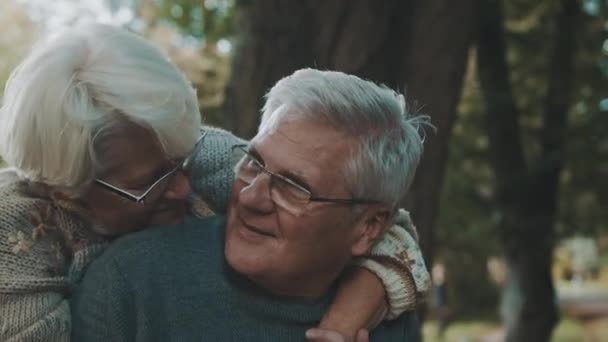 Gelukkig oud stel knuffelend in het park. Senior man flirt met oudere vrouw. Romantiek op hoge leeftijd op herfstdag — Stockvideo