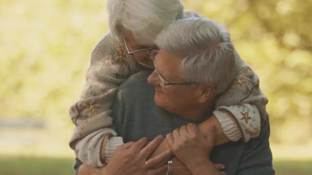 Feliz pareja de ancianos abrazándose en el parque. Hombre mayor coqueteando con una anciana. Romance a la vejez bailando en el día de otoño — Vídeos de Stock