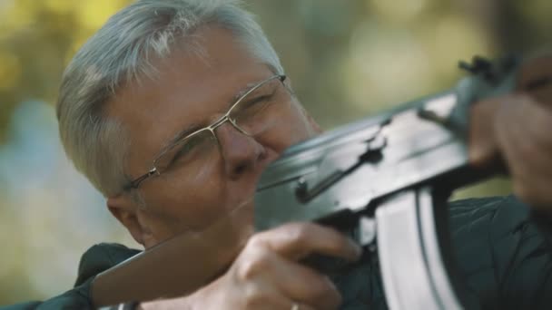 Elderly gray haired man holding a gun in his hands. Hunting season — Stock Video