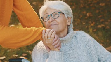 Ormanda romantik bir sonbahar günü geçiren yaşlı çift. Ağaca sarılmak ve gülümsemek