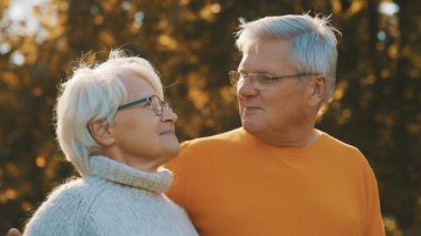 Yaşlılıkta romantizm. Emekli çift sonbahar pikniğinin tadını çıkarıyor. Birbirinize bakın.