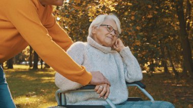 Ormanda romantik bir sonbahar günü geçiren yaşlı çift. Ağaca sarılmak ve gülümsemek