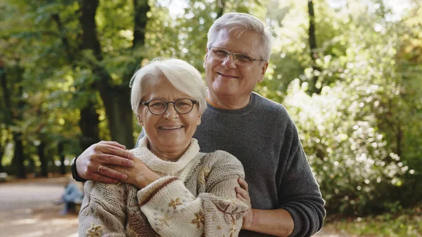 Feliz pareja de ancianos abrazándose en el parque. Hombre mayor coqueteando con una anciana. Día de otoño —  Fotos de Stock