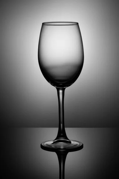 transparent wine glass stands on black glossy glass