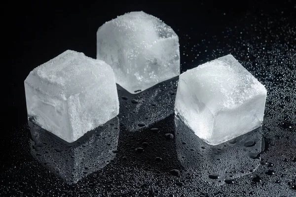 Siyah cam üzerinde üç buz küpü.