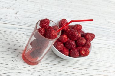 Çilekli şeffaf cam ve çilekli beyaz tabak.