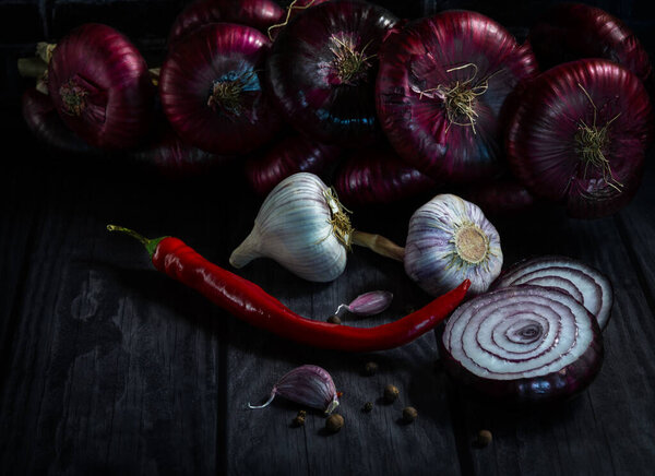purple onion, sweet salad variety "Yalta", garlic and red pepper on a dark wooden background. Gifts of autumn
