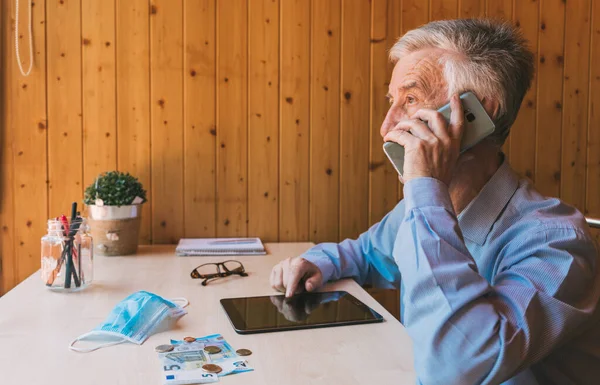 Concerned businessman talks on the phone about the economic impact of coronavirus, the economic crisis in international markets. Senior man talking in his office about the financial market.