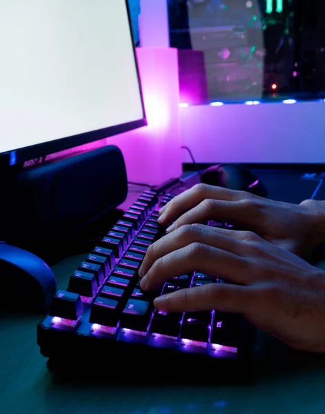 Image of man\'s hands typing. Hands of a player on a keyboard. Background is Lit with led Lights.