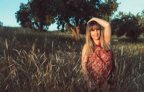 Horizontal photograph of a young woman with bold looks posing stylishly smiling in the field. Enjoying nature on the summer vacation at sunset.