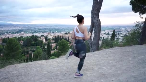 年轻的女运动员跑到现场 一个夏日的下午 在Alhambra前的训练中 穿着腿和运动鞋的慢动作女运动员在地上跳跃和抬腿 — 图库视频影像