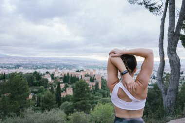 Tatilde olan sağlıklı bir kadın yaz öğleden sonra Alhambra 'nın önünde şehir üzerinde esneme egzersizleri yapıyor..