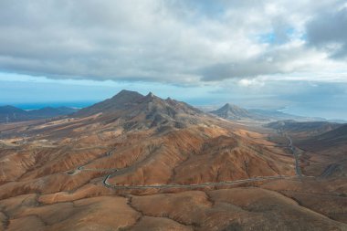 Fuerteventura 'nın çorak, güneşli manzarasında eğri büğrü bir dağ geçidinin göz kamaştırıcı manzarası..