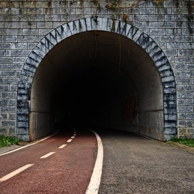 pedestrian and bicycle path leading into the darkness of a tunnel